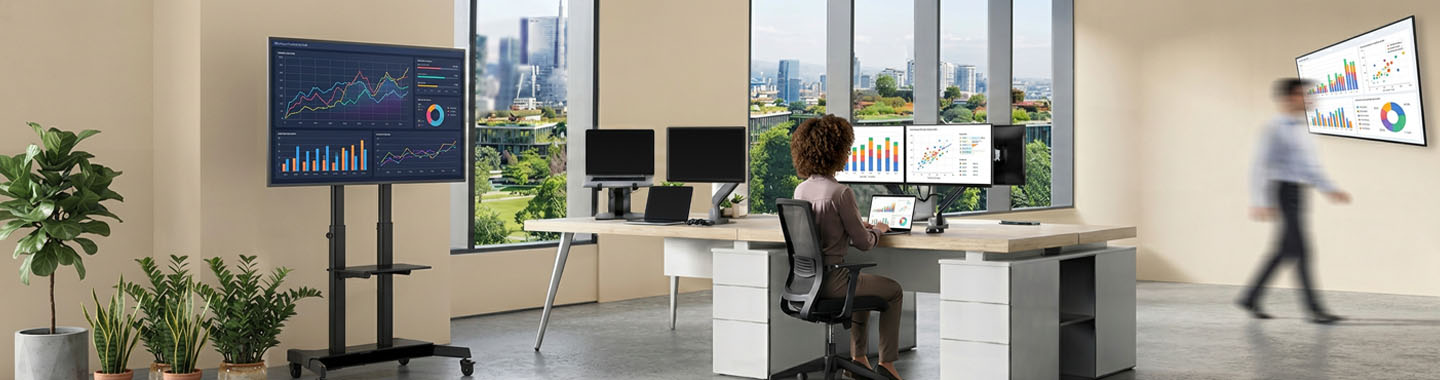 Modern office environment with multiple screens and people conducting data analysis and presentations