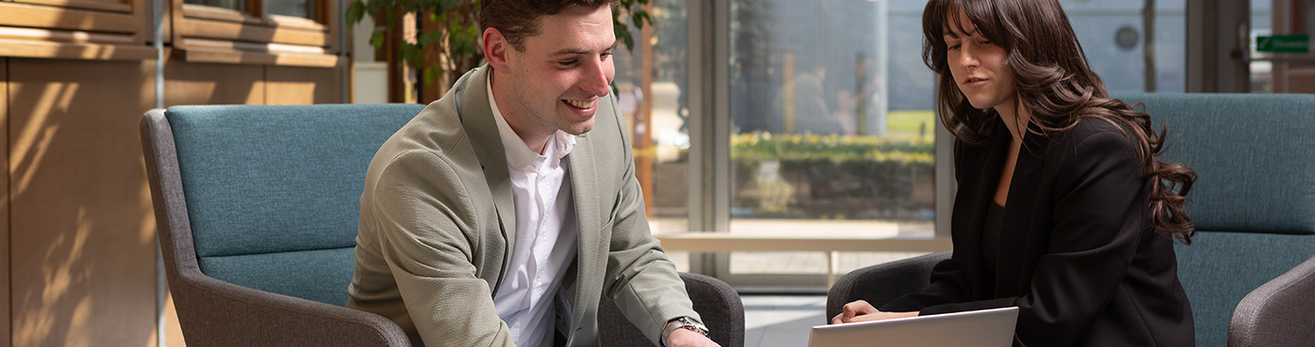 Two people in a modern office engaged in discussion and collaboration with a laptop in a bright workspace